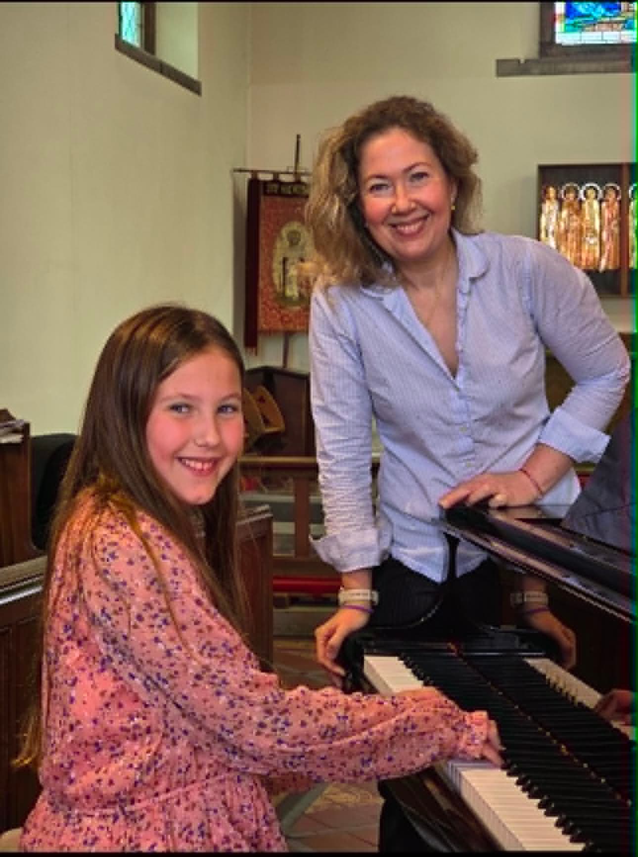 A teacher guiding a student through a piece at the piano
